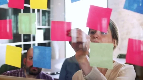 Team of young managers look on sticker on glass during business meeting and work Stock Footage 80083701