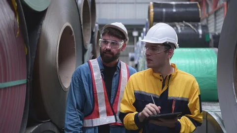 A team of young men working in a warehouse storing rolls of metal sheets. Stock Footage 254764669