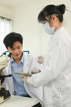 Team of young research scientists using digital tablet and discussing about new Foto stock