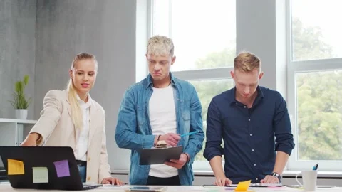Team of young startupers is working at the table in the office, discussing the Stock Footage 160470062
