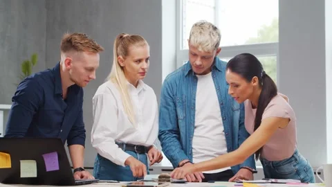 Team of young startupers is working at the table in the office, discussing the Stock Footage 160565250