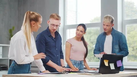 Team of young startupers is working at the table in the office, discussing the Stock Footage 160925626