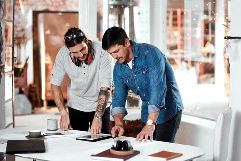 Teamwork accomplishes great things. two young businessmen working together in an Stock Photos