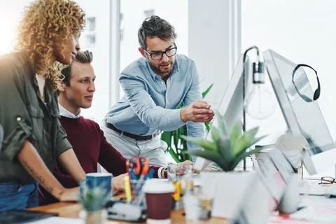 Teamwork is always the answer. a group of colleagues using a computer together Stock Photos