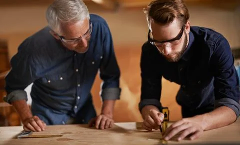 Teamwork, carpenter and apprentice in workshop, wood measurement and designer Stock Photos