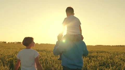 Teamwork. child sits on his father's shoulders rides. happy family in the wheat Stock Footage 248418496
