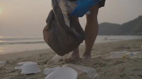 Teamwork cleaning plastic on the beach. Volunteers collect trash in a trash bag. Stock Footage 237944757