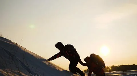Teamwork concept. help you partner climb snowy mountain with backpack. hiking Stock Photos