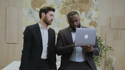 Teamwork concept. Two smiling modern businessmen using laptop together, african Stock Footage 196126618