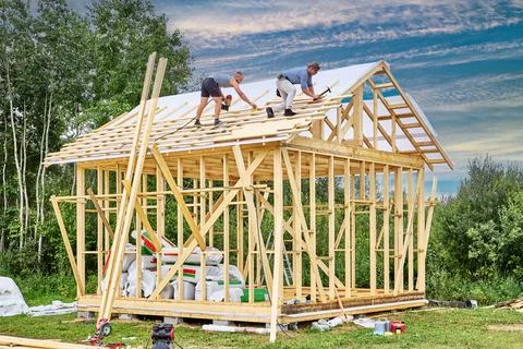 Teamwork of construction crew installing roof battens over windproof membrane Stock Photos
