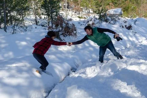 Teamwork couple is  helping each other on snow in winter. Stock Photos