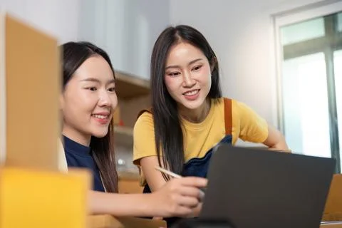 Teamwork in E-commerce. Women collaborating on a laptop in a modern workspace. Stock Photos
