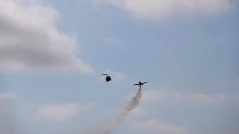 Teamwork of a flying retro UH-1 helicopter and a smoking aerobatic plane Stock Footage 317478172