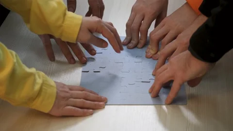 Teamwork. Group of people at table are putting together puzzle. Path to team Stock Footage 154999593