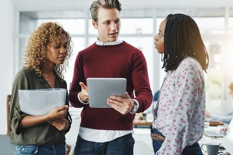 Teamwork makes the job so much simpler. a group of colleagues using a digital Stock Photos