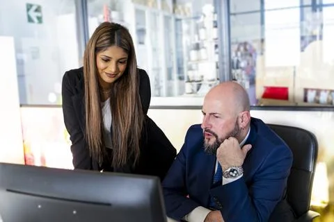 Teamwork meeting in office in front of computer between two male and female.. Stock Photos