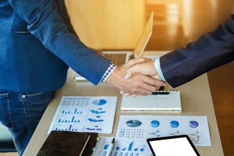 Teamwork process, Close-up of two business people shaking hands while sitti.. Stock Photos
