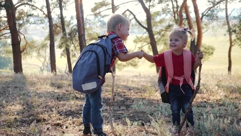 Teamwork. Two children a boy and a girl walk through the woods holding out each Video stock 132206165