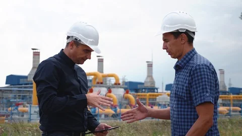 Teamwork. Two helmeted engineers are testing the operation of a gas processing Stock Footage 119884584