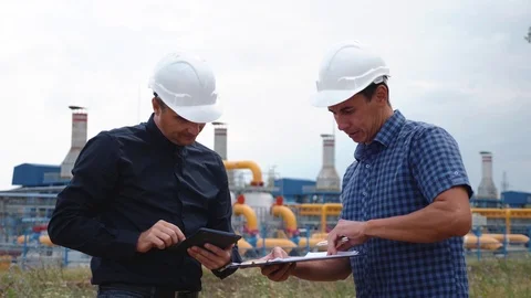 Teamwork. Two helmeted engineers are testing the operation of a gas processing Stock Footage 120059123