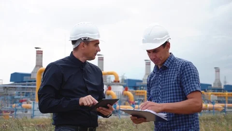 Teamwork. Two helmeted engineers are testing the operation of a gas processing Stock Footage 120275056