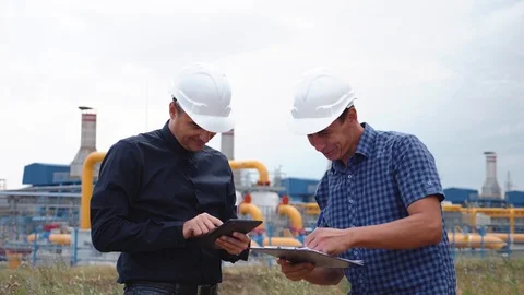 Teamwork. Two helmeted engineers are testing the operation of a gas processing Stock Footage 120691460