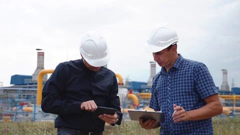 Teamwork. Two helmeted engineers are testing the operation of a gas processing Stock Footage 121153508