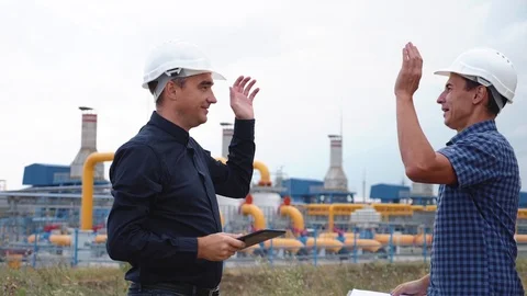 Teamwork. Two helmeted engineers are testing the operation of a gas processing Stock Footage 123481900