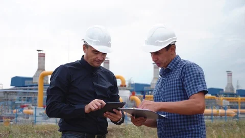 Teamwork. Two helmeted engineers are testing the operation of a gas processing Stock Footage 128413608