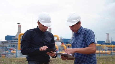 Teamwork. Two helmeted engineers are testing the operation of a gas processing Stock Footage 129001442