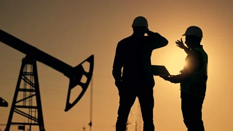 Teamwork. Two workers in hard hats at sunset. Working oil pump silhouette. Two Vídeos de archivo 233487640