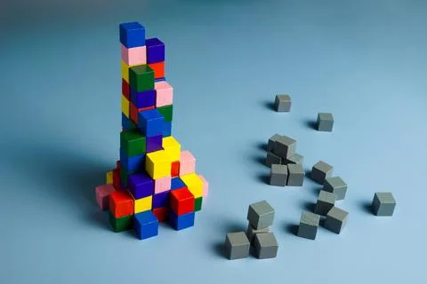 Teamwork, unity and diversity. Gray cubes and a pyramid of multi-colored ones. Stock Photos
