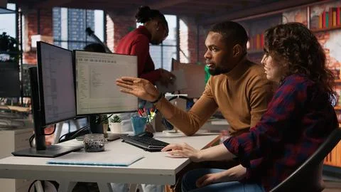 Teamworking colleagues using computer in software development agency Stock Photos