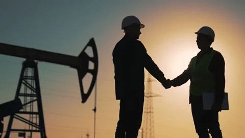 Teamwork.Oil engineer in helmet work with an oil pump.Silhouette of worker in Video stock 204841473