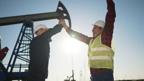 Teamwork.Oil engineer in helmet work with an oil pump.Silhouette of worker in Vídeo Stock 252109997