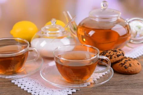 Teapot and cups of tea on table on light background Stock Photos