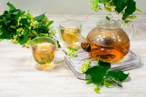 Teapot and two cups of tea with a linden tree on a wooden table. Healing tea. Stock Photos