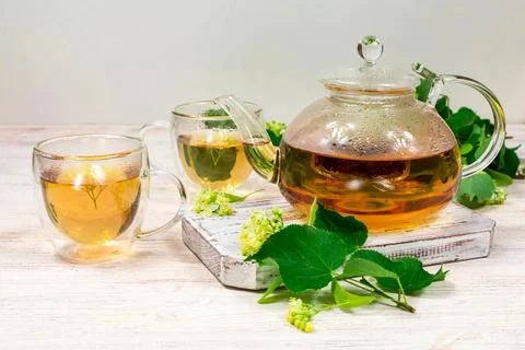 Teapot and two cups of tea with a linden tree on a wooden table. Healing tea. Stock Photos