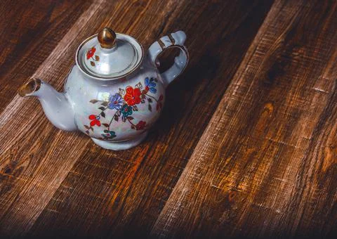 A teapot on the background of an ancient torn texture. Action. Beautiful shin Stock Photos