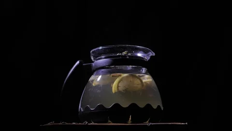 Teapot with a hot tea on a dark background. Small dust-like particles falling Stock Footage 83486777