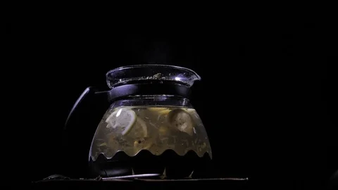 Teapot with a hot tea on a dark background. Small dust-like particles falling Stock Footage 83486793