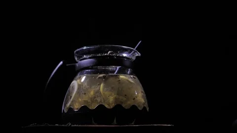 Teapot with a hot tea on a dark background. Small dust-like particles falling Stock Footage 83486809