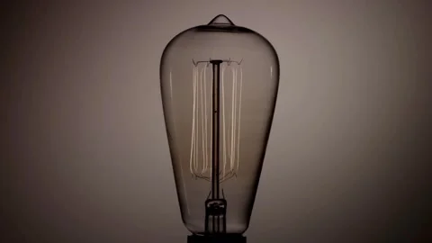 Teardrop shaped edison bulb vertical filaments glow warm light Stock Footage 329656857