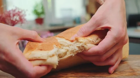 Tearing fresh baked bread with hands in the kitchen Video stock 252437674