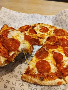 Tears off a slice of pizza from everything with pepperoni and cheese Stock Photos