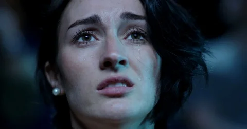 Tears stream down the face of a young woman while watching an emotional movie Stock Footage