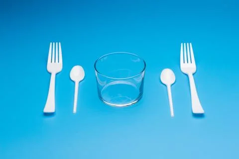 Teaspoon and plastic fork and glass tumbler Stock Photos