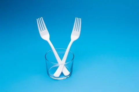 Teaspoon and plastic fork and glass tumbler Stock Photos