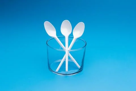 Teaspoon and plastic fork and glass tumbler Stock Photos