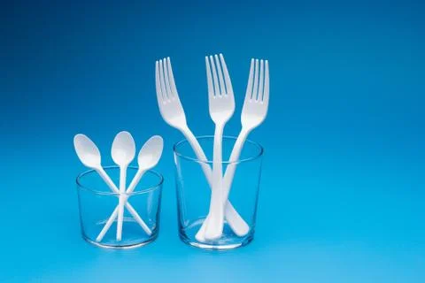 Teaspoon and plastic fork and glass tumbler Stock Photos